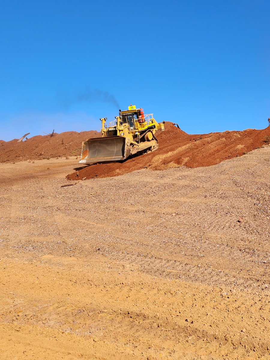 bull dozer going down a hill of red dirt